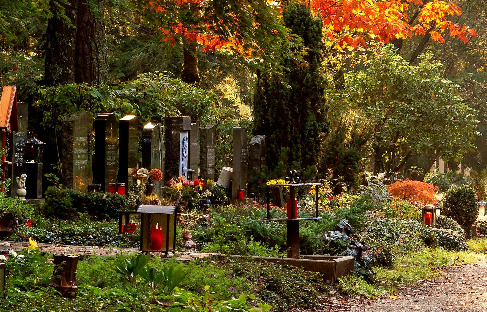 Weg, der über den Friedhof führt mit schön geschmückten Gräbern bei Herbst
